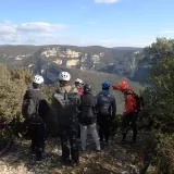 Un groupe de personne descendu de leur VTT pour observer la vue sur des montagnes et écouter les indications d'un animateur